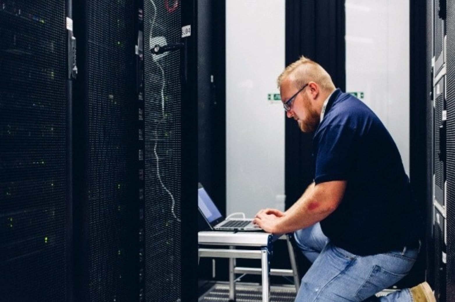 Will Sale of The Tec Wizard working on a laptop between server racks in a datacentre